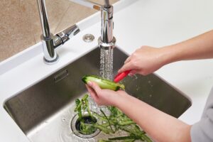 Woman slicing cucumber and putting slices down her garbage disposal