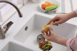 A person peeling vegetables in a white sink in Waldorf.